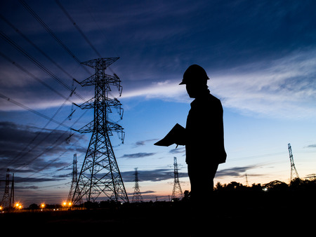 silhouette man of engineers standing at electricity station over Blurred electricity powerの写真素材