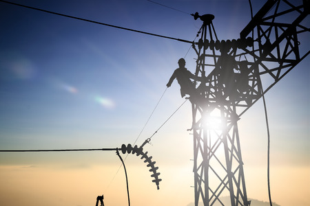 Silhouetteblack man  electrical engineer and electrical workers are installing high voltage systems over blur night cityの写真素材