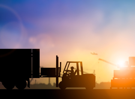 Silhouette driver of the truck was put in the car to transport cargo to customers, accurately and securely over blurred pastel background sunset shipping. Heavy industry and Transportation concept.の写真素材