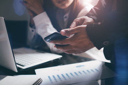 Young businessmen analyze graphs to meet goals set over blurred Business graph on the table in office .Film tones and Light fair. select focusの写真素材