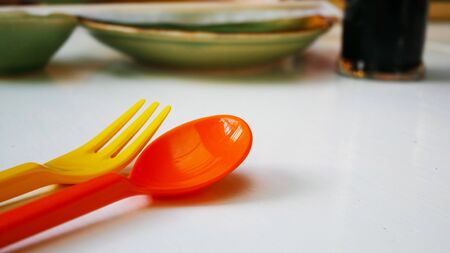 Prepare orange spoon and yellow fork for a kid.