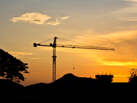 Industrial landscape. Construction cranes and concrete structure at silhouettes sunseの写真素材