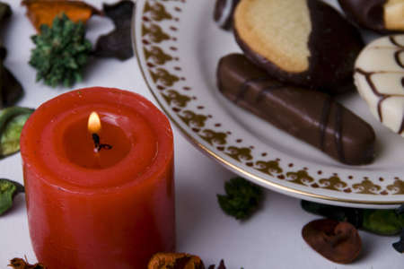 Romantic red candle with dry petals and biscuits on white backgroundの写真素材