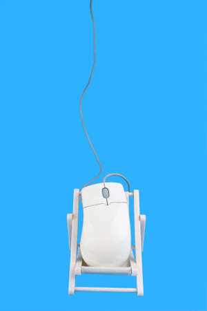 A computer mouse resting on the deck chair with blue backgroundの写真素材