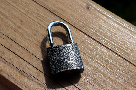 An open metal padlock lies on a wooden surface. Horizontal photo, close-upの写真素材