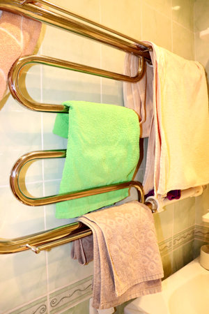 Cotton towels for face, hands and body hanging on heated towel rails, chrome radiators in home bathroom - vertical photo, close-upの写真素材
