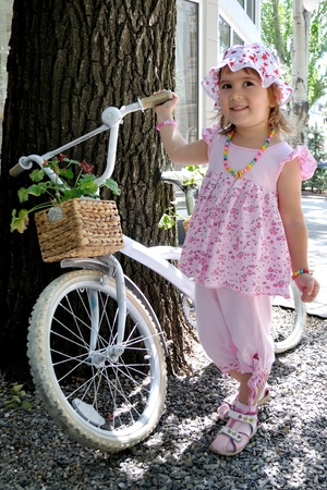 Little girl in pink next to a bicycleの写真素材