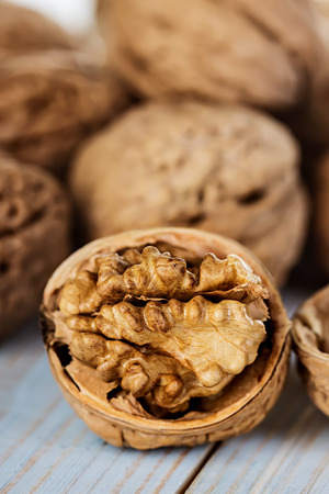 Half walnut kernel and whole walnuts on a wooden background closeupの写真素材