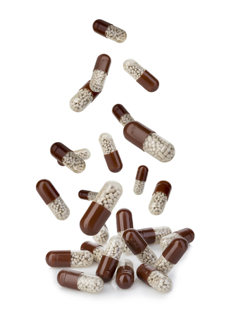 Falling brown medical pills close-up isolated on white background.の写真素材