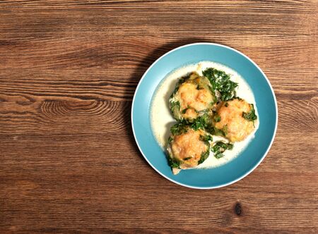 baked meatballs in spinach sauce with cheese on a wooden table in a plateの写真素材