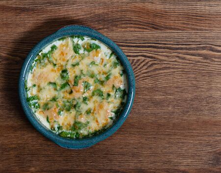 baked cutlets in spinach sauce with cheese on a wooden table in a baking dishの写真素材