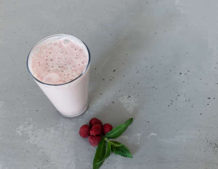 milkshake in glass with cocktail pipe, raspberries and mint leaf on gray concrete backgroundの写真素材