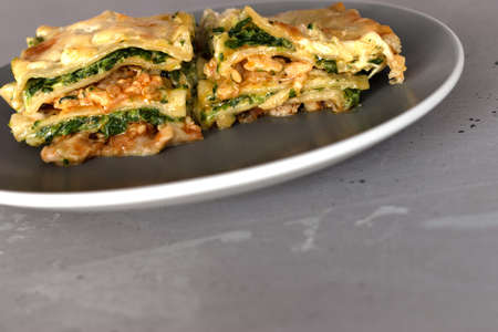 a piece of lasagna in a plate on a gray backgroundの写真素材