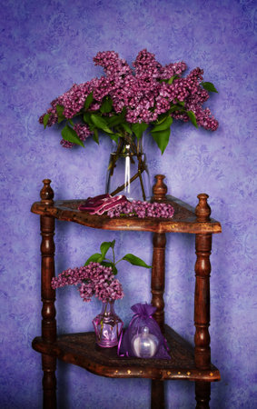 A bouquet of beautiful lilacs in a glass vase on a wooden shelf. Still life of fresh flowersの写真素材