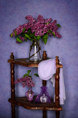 A bouquet of beautiful lilacs in a glass vase on a wooden shelf. Still life of fresh flowersの写真素材