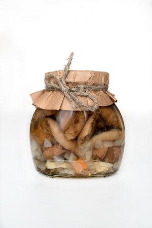 homemade fermented mushrooms in a glass jar on a white background. Pickled and wild mushrooms close-upの写真素材