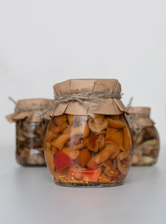 Delicious homemade pickled mushrooms in a glass jar on a white background. Canned mushrooms and wild mushrooms close-up, copy space;の写真素材