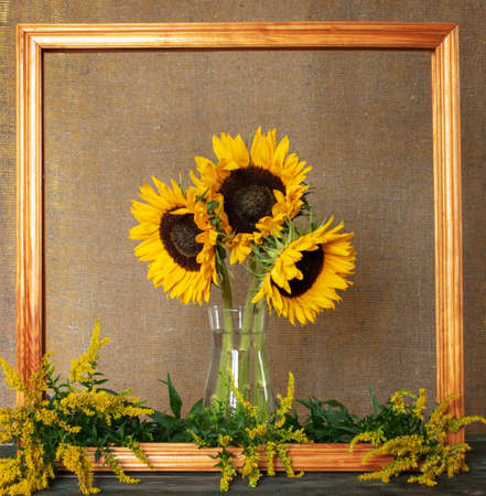 A bouquet of bright sunflowers in a wooden frame on canvasの写真素材
