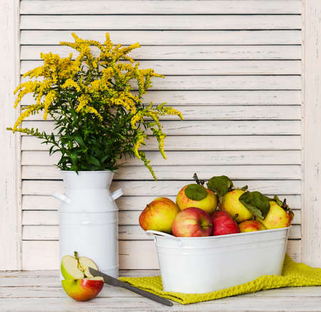 Bouquet of yellow wildflowers and fresh apples on a white wooden rustic table.の写真素材
