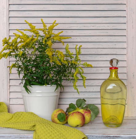 Natural products from our own garden. fresh apples and yellow wildflowers on a white rustic table.の写真素材