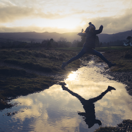 A Teen Jumps Over Water On A Nature Hikeの写真素材
