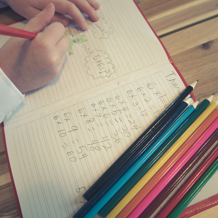 Child Draws Pictures In School Math Notebook