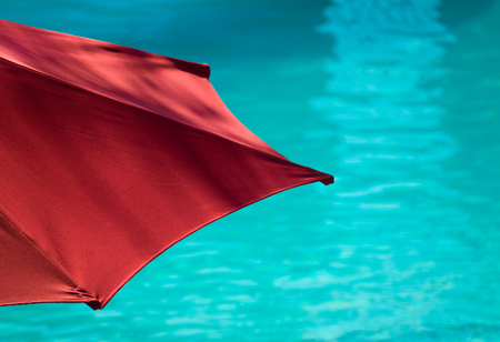Red Parasol Beside Turquoise Swimming Poolの写真素材