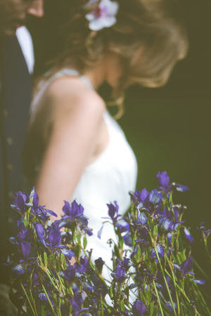 Wedding Couple in Background Behind Irisesの写真素材