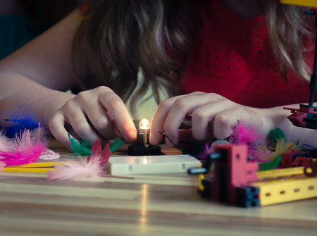 Female Child Wires a LIghtbulb Playing With Electronics Kit