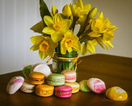 Macarons and Meringues on a Country Kitchen Table With a Bouquet of Fresh Daffodils