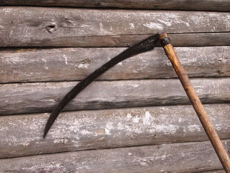 scythe against the backdrop of a log wallの写真素材