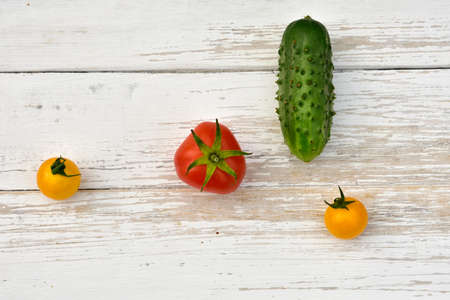 red tomato, two yellow small tomatoes and a cucumber, top viewの写真素材