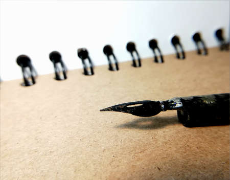 a pen smeared in black ink against a background of brown paper. taken in close-up