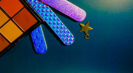 cosmetics eye shadow and nail files on a blue background