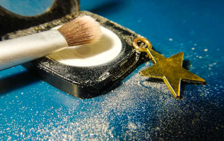eye shadow and brush and a star symbol on a blue background