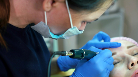Closeup permanent makeup. Cosmetologist applying permanent tattooing of eyebrows in beauty salon....