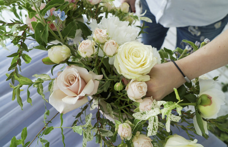 Flowers event wedding decoration. Closeup florist hands creating spring colorful bouquet arrangement. Process of preparing floral composition for celebrating party.の写真素材