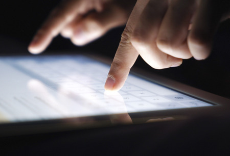 Closeup fingers typing texting a message on tablet. Network, communication, technology conceptの写真素材