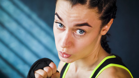 closeup portrait beautiful young boxing woman training punching in gym. Fit female preparing to...