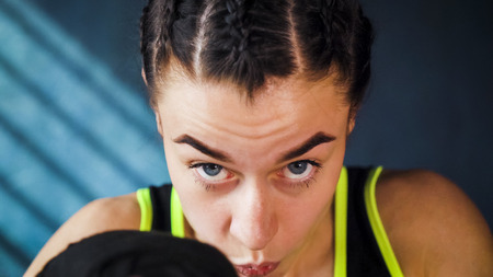 closeup portrait beautiful young boxing woman training punching in gym. Fit female preparing to boxing competition. Wellness, fighting, motivation, martial arts, self defense conceptの写真素材