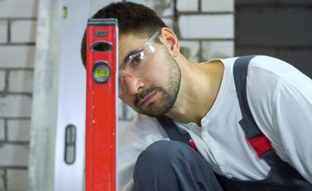 young construction worker looking at bubble level