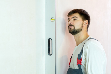 builder checks evenness of freshly built wall with bubble level with free space