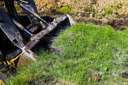 green field being shoveled by bulldozer during earthmoving works