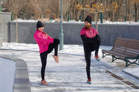 Friends doing exercises in winter park togetherの写真素材