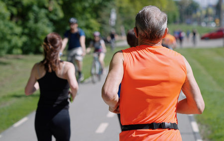 Gray-haired man in sportswear jogging in park
