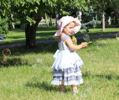 Little girl blowing soap bubbles in a city park.の写真素材