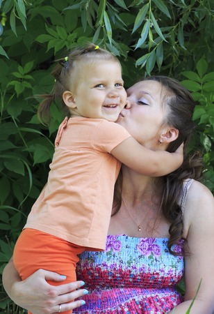 Mother kissing her little daughter in the park.の写真素材