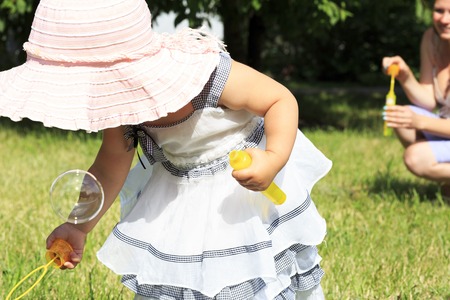 Beautiful mother and daughter blow bubbles in a city park.の写真素材