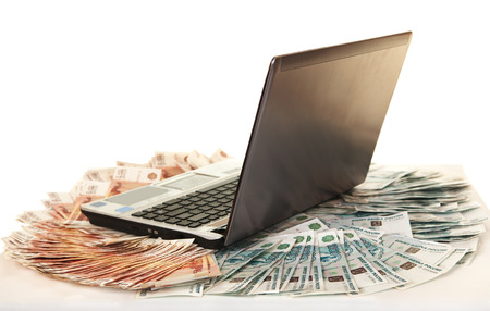 Laptop on large pile of bills five thousandthの写真素材