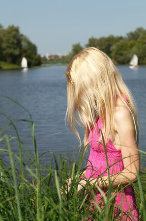 Sad blonde is waiting on the riverbank.の写真素材